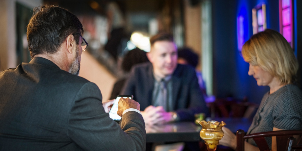 Two businessmen and a woman engaged in discussion around a table, representing AZ Luxe's professional concierge service